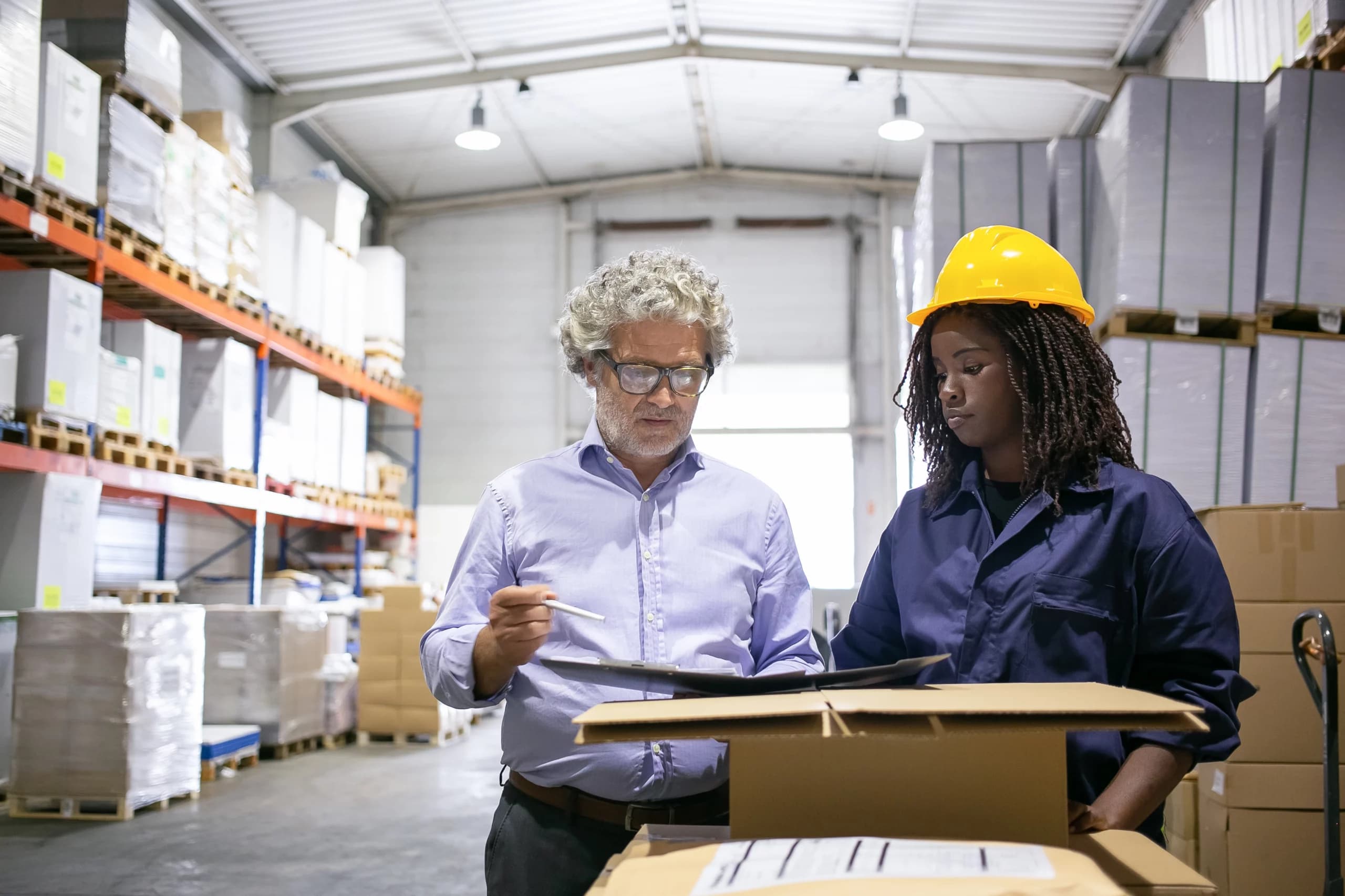 Deux professionnels du transport et de la logistique analysant un audit Qualiopi sur ordinateur dans un entrepôt